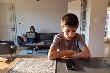 Adolescent regardant son smartphone à la maison, illustrant les enjeux de l’accès aux réseaux sociaux et du contrôle parental avant 15 ans