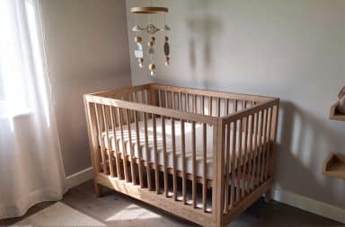 Lit bébé en bois avec matelas bébé 70x140 bien ajusté, installé dans une chambre lumineuse et apaisante, offrant un couchage sécurisé et confortable pour le sommeil du nourrisson.