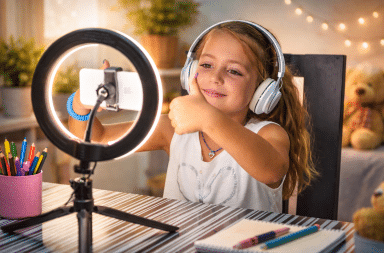 enfant filmant une vidéo avec smartphone et ring light à la maison