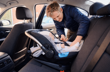 parent vérifiant son bébé dans un siège auto à l’arrière d’une voiture